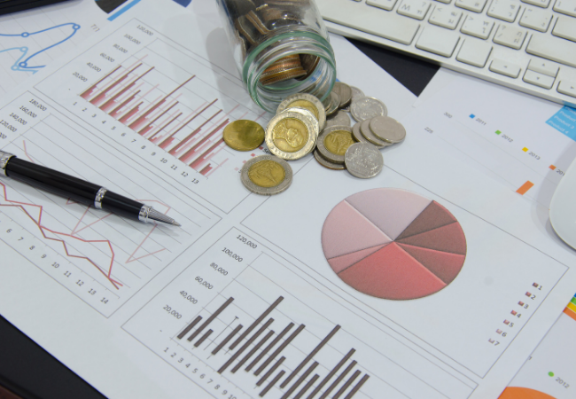 immagine di documento commerciale con  grafico finanziario e penna e monete su una scrivania
