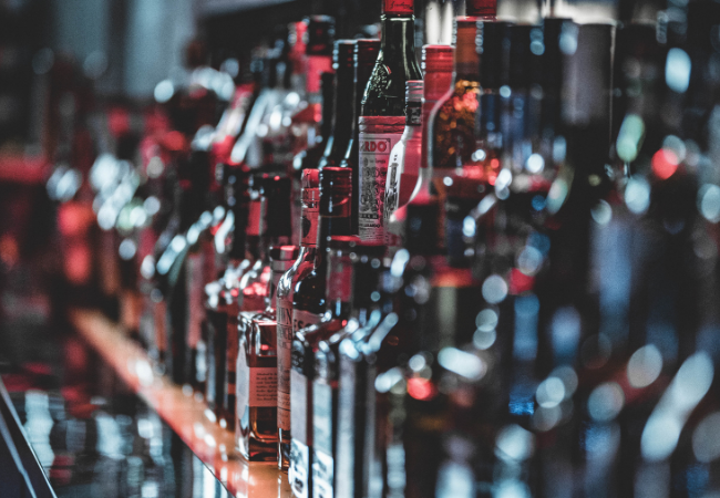 immagine di bottiglie di alcolici in fila su uno scaffale
