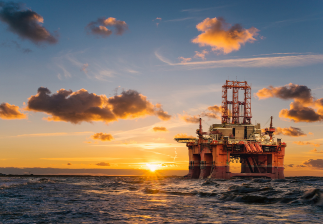 Immagine di una piattaforma petrolifera al tramonto.