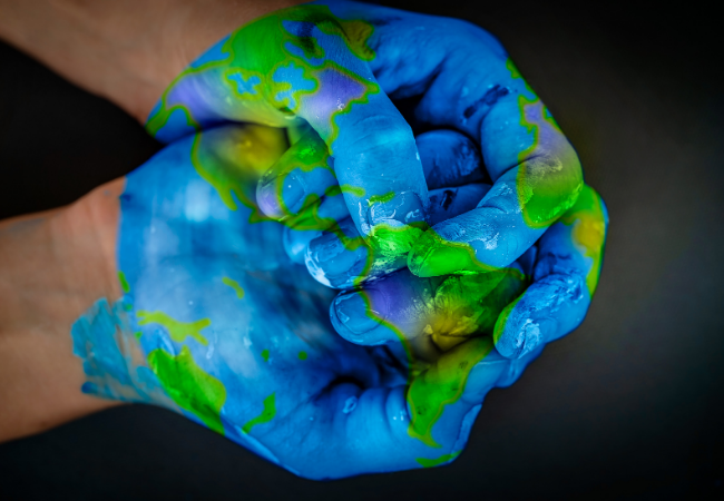 immagine di mani chiuse dipinte per costituire il globo terrestre