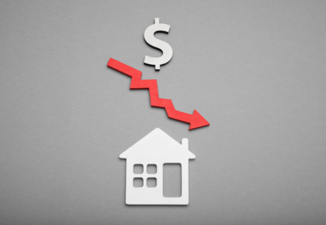 Immagine di una casa disegnata con una freccia rossa che va verso il basso e il simbolo del dollaro sopra.