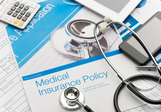 Immagine di uno sfigmomanometro e di un foglio con su scritto "Medical Insurance Policy".