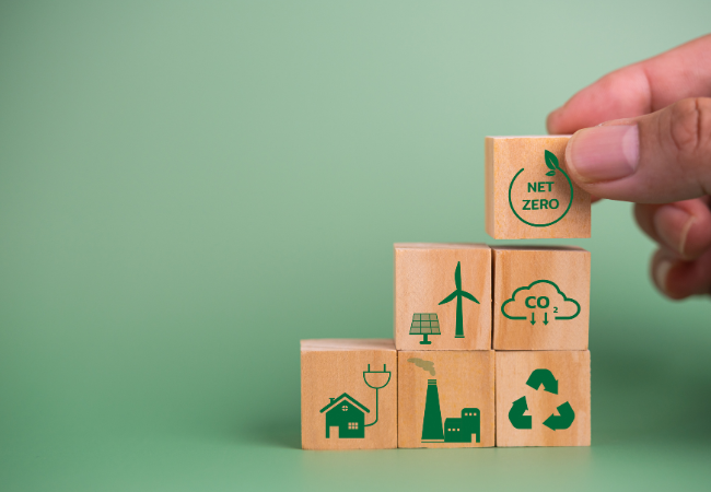  Immagine che raffigura blocco cubico di legno, che raffigura l'obbiettivo emissioni zero e alcune tecnologie per la produzione di energie pulita su sfondo verde.