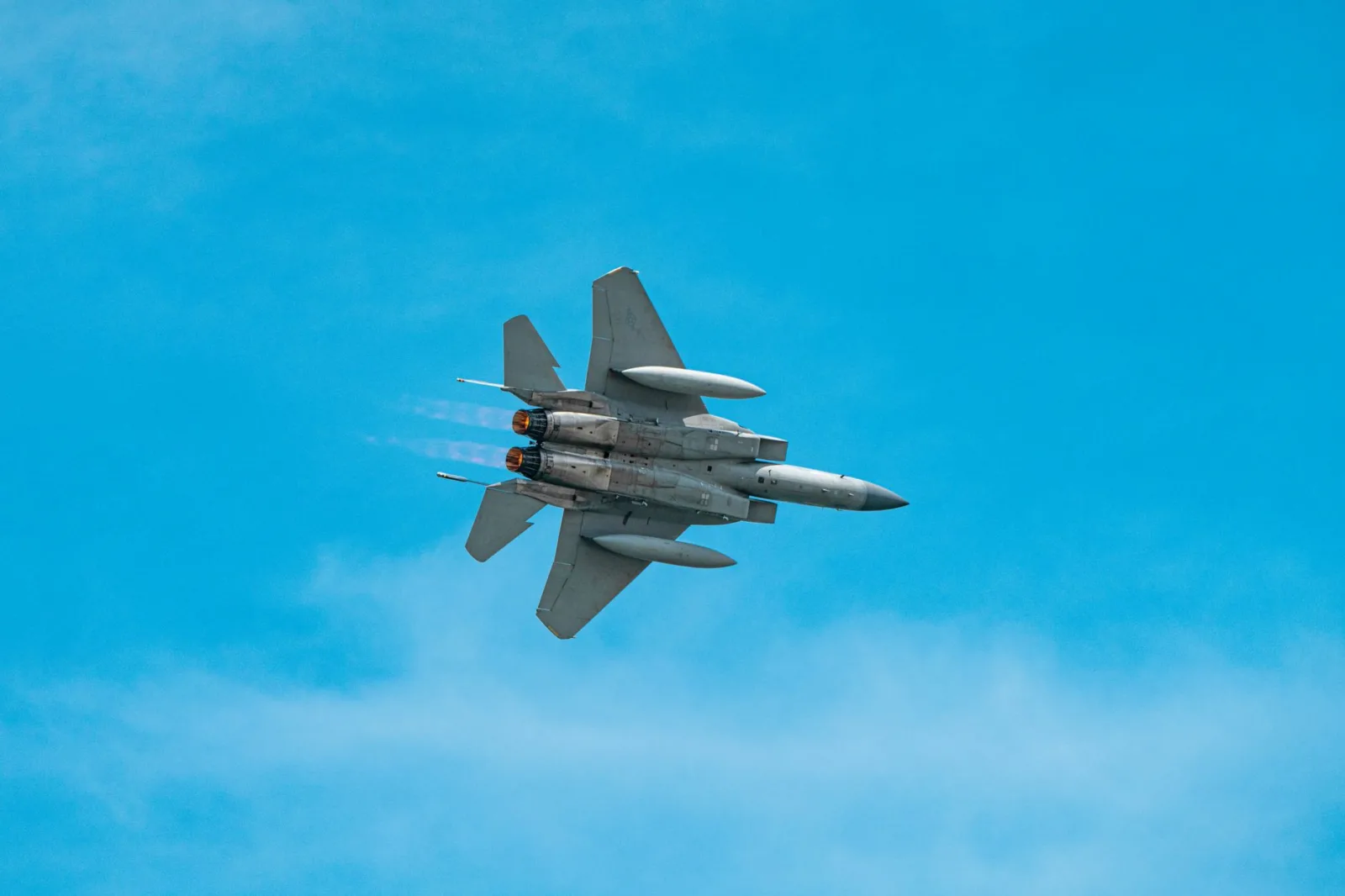 A military jet aircraft soaring through a clear blue sky, showcasing agility and power.