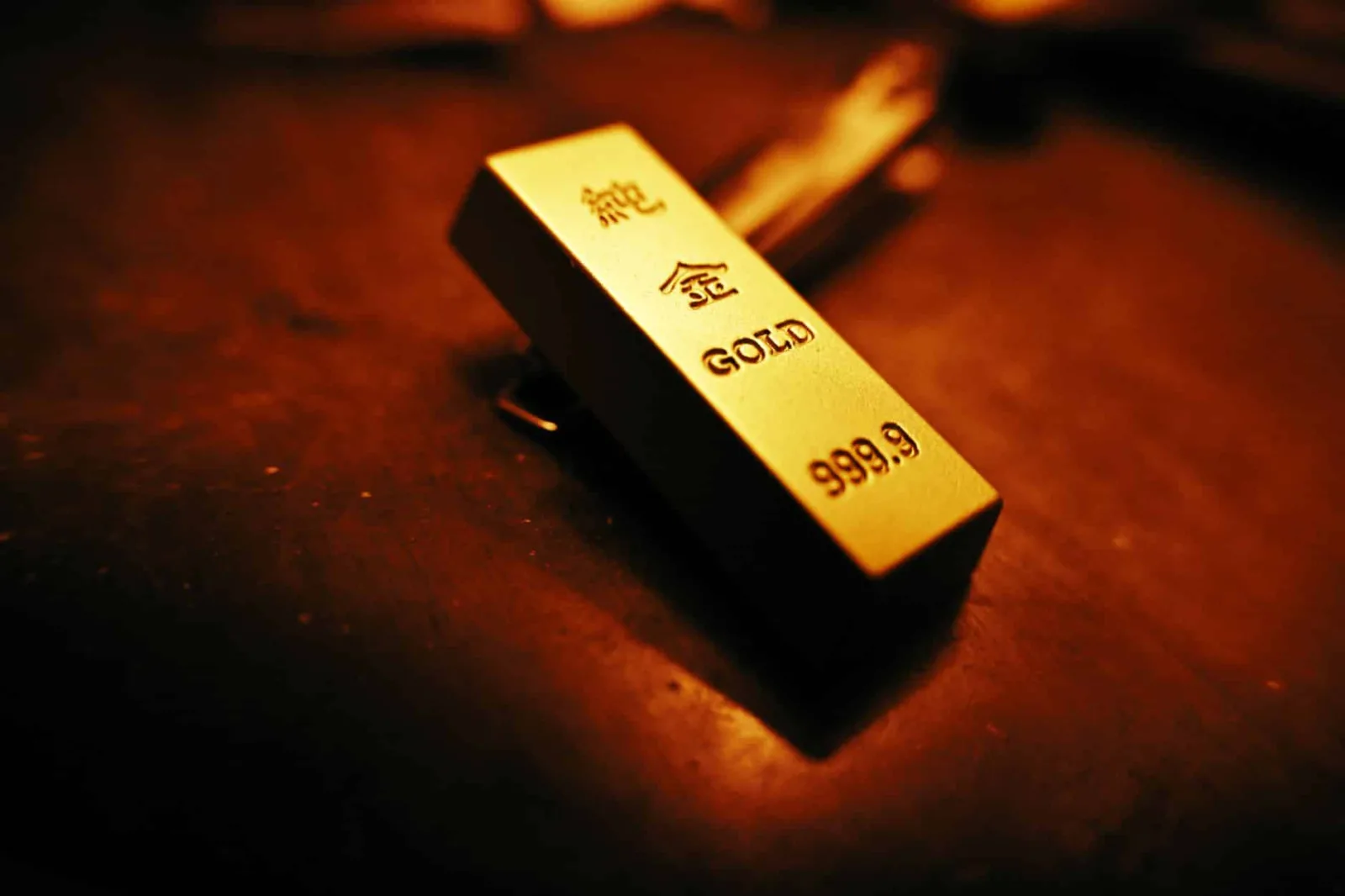 A striking close-up of a gold bar showing inscriptions, captured with warm lighting.