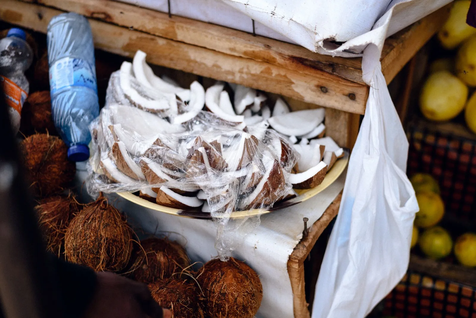 Coconut slices and whole nuts on display at an outdoor market in Jos, Nigeria.