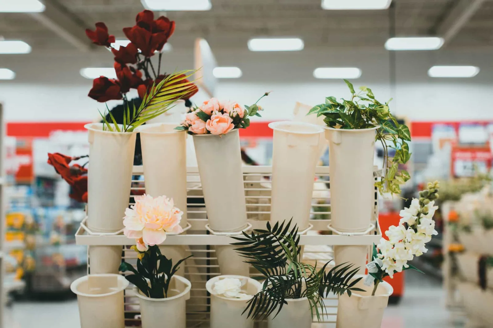 Artificial flowers in display buckets at a retail store aisle showcasing vibrant decor options.