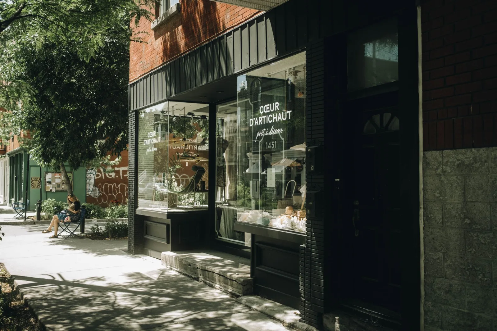 A quaint urban storefront with a glass window on a sunny summer day.