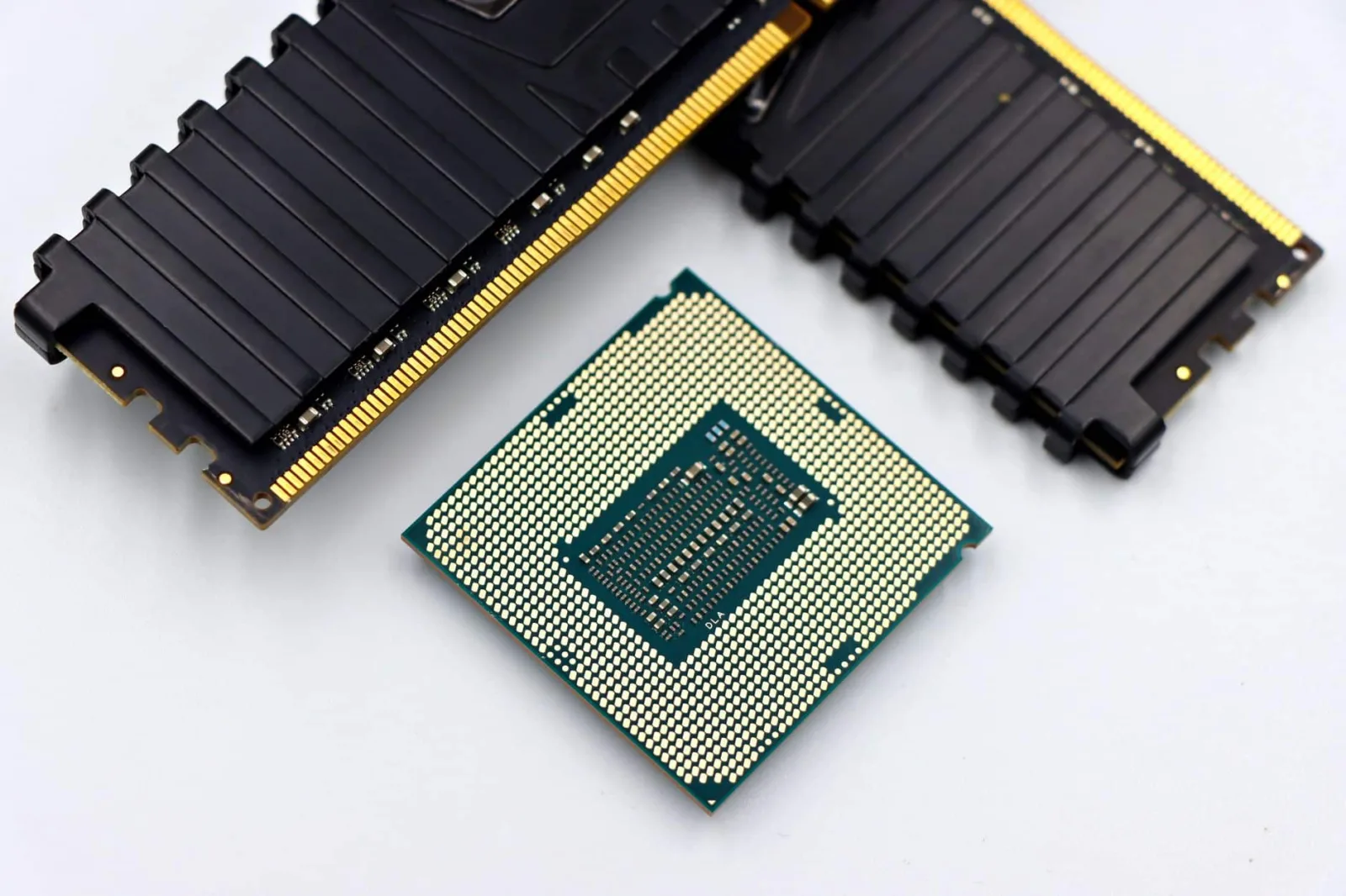 A CPU and RAM sticks displayed on a white surface, showcasing computer hardware components.