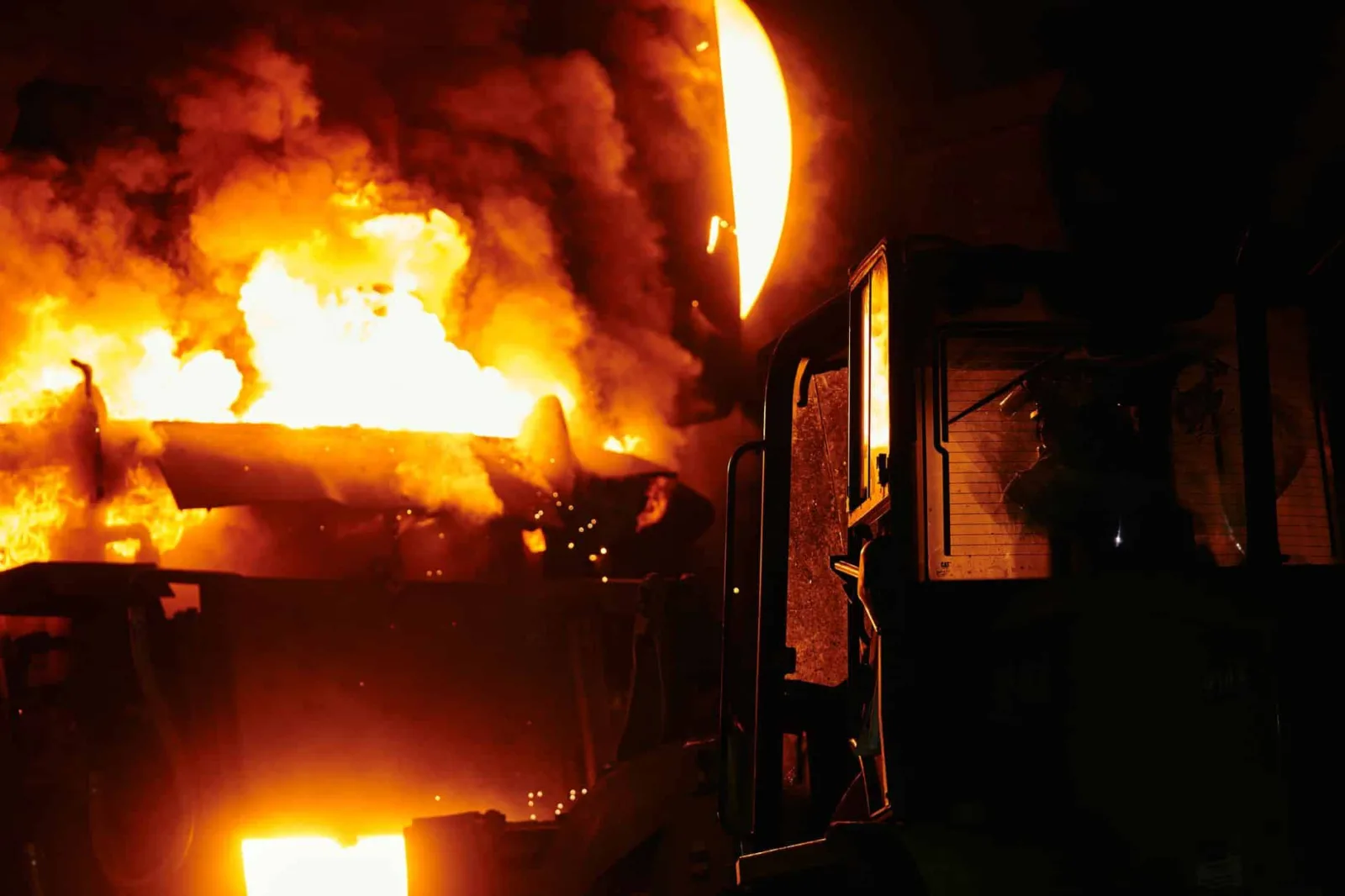 A dramatic scene of molten steel pouring in an industrial setting during nighttime.