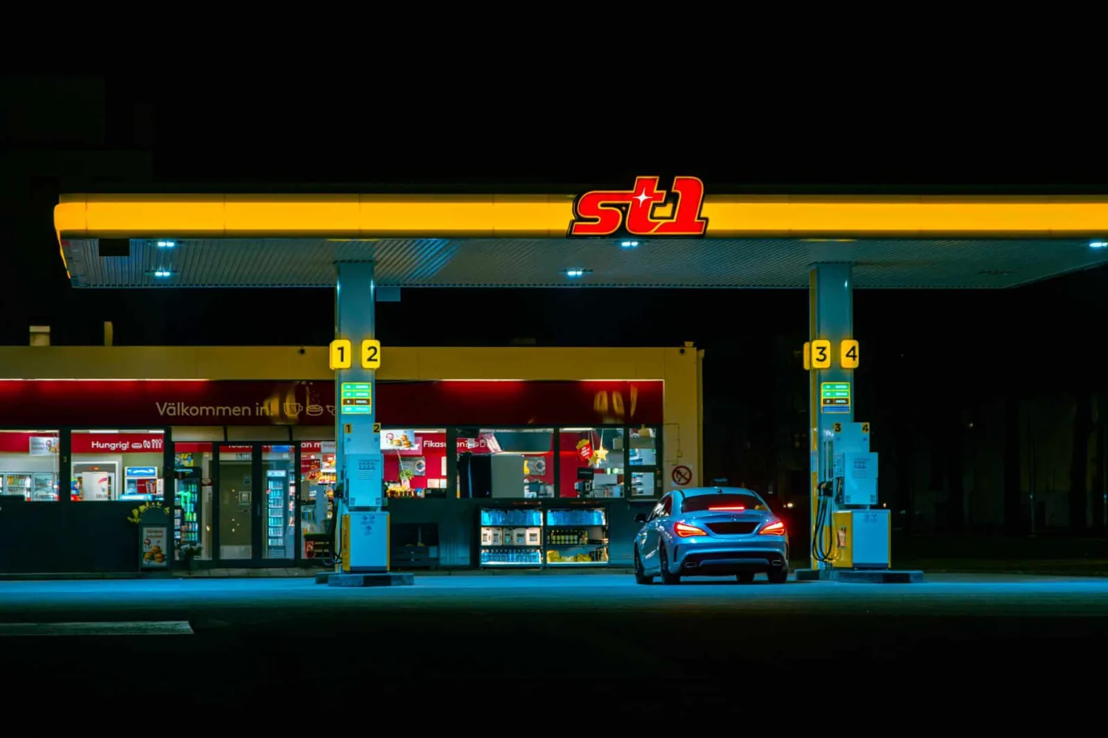 A car refuels at the illuminated St1 gas station in Jönköping, Sweden at night.