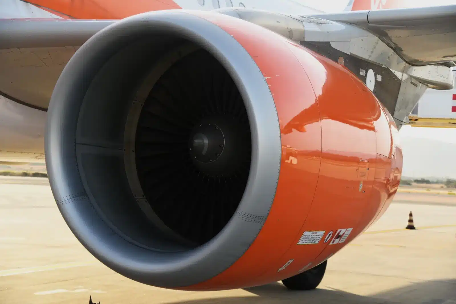 Detailed view of an orange jet engine of a commercial airplane in Sardegna, Italy.
